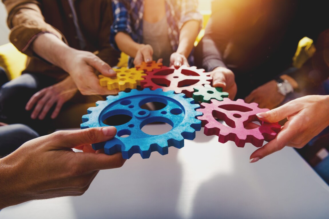 Des mains unissent des engrenages colorés pour symboliser l'interconnexion dans un projet