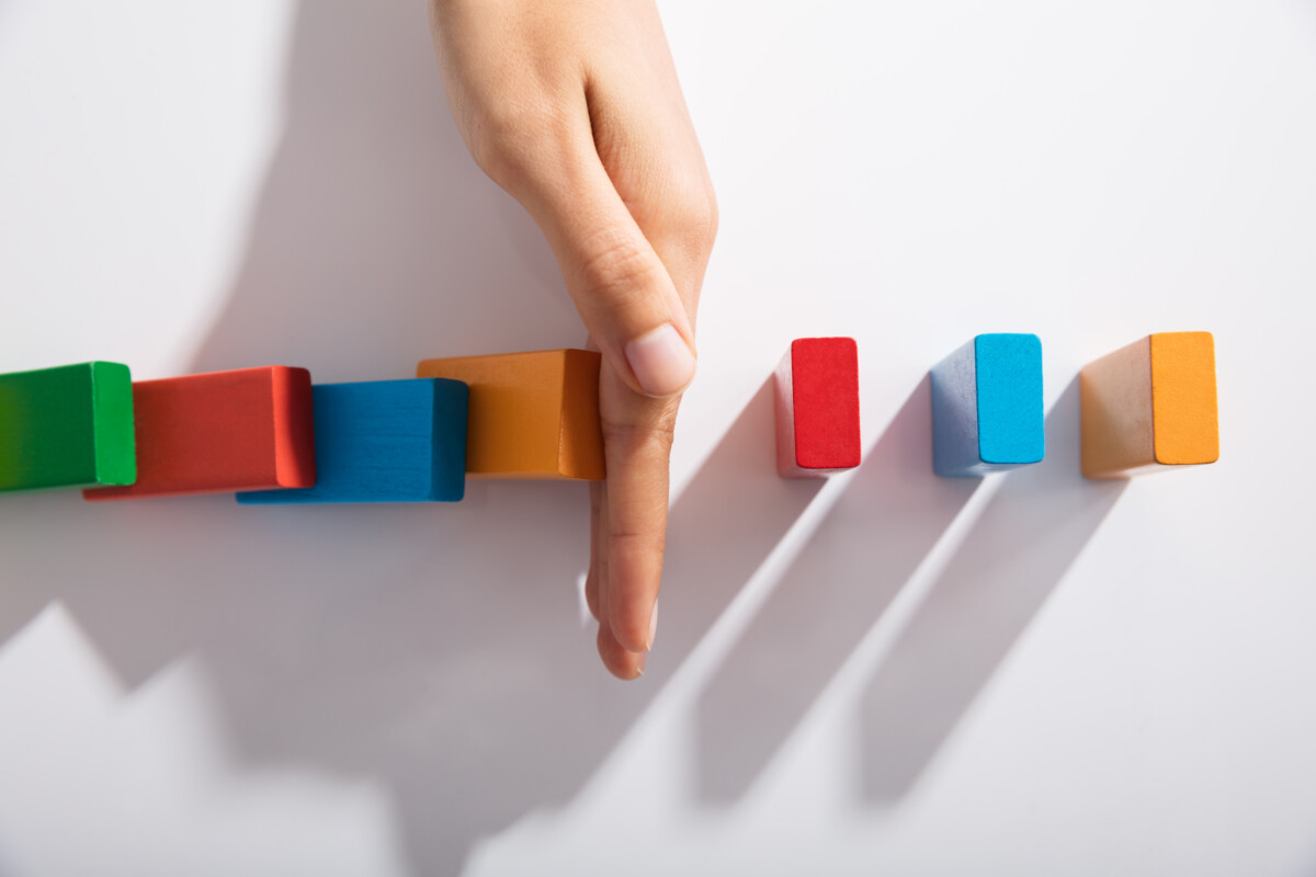 Une main interrompt la chute de petits blocs colorés en cascade