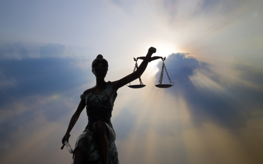 Statue de la justice tenant une balance déséquilibrée, éclairée par une lumière céleste perçant les nuages - une image symbolique illustrant la nécessité d’équité dans la gestion d’un conflit au travail. Lorsqu’un déséquilibre perçu s’installe entre les droits, les devoirs ou la reconnaissance des parties, le conflit peut s’intensifier. La justice, ici aveugle mais éclairée, rappelle l'importance d’une médiation impartiale pour restaurer la confiance et l’équilibre relationnel en entreprise.