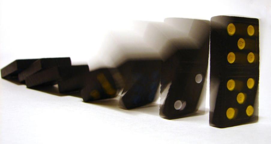Une série de dominos noirs est en train de tomber, entraînés dans un mouvement de chute en cascade. Cette scène illustre l'effet domino provoqué par un conflit en entreprise non résolu, où un seul déséquilibre initial — mal géré ou ignoré — déclenche une réaction en chaîne. Chaque pièce symbolise un service, une personne ou une décision, montrant comment l’absence d’intervention rapide dans un conflit en entreprise peut compromettre la stabilité globale de l’organisation.