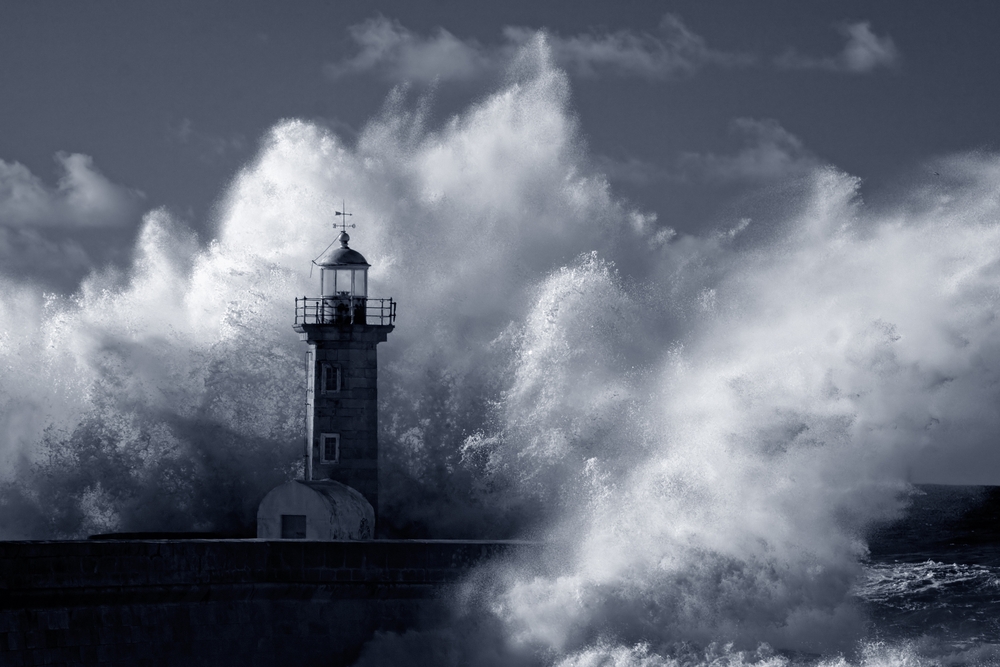 Photographie spectaculaire d’un phare ancien battu par une immense vague, en pleine tempête marine. L’écume se fracasse violemment contre l’édifice, mais le phare reste debout, immobile, solide, au cœur du chaos. L’image évoque la résilience d’une entreprise confrontée à un conflit au travail, mais qui tient bon grâce à une stratégie de gestion intégrée des tensions. Le phare symbolise ici les fondations solides, les repères clairs et les outils appropriés mis en place pour résister, absorber, et transformer les secousses du conflit au travail en leviers de stabilité et de confiance.