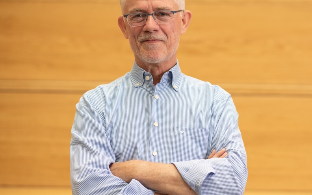 Portrait de Patrick Namotte, expert en dialogue social, bras croisés, regard calme et affirmé. Il se tient devant un fond en bois clair, évoquant la rigueur et la chaleur humaine. Cette image illustre la posture d’un médiateur expérimenté, à la fois accessible et solide, engagé dans la régulation des tensions sociales, la gestion des conflits collectifs et l'accompagnement des entreprises belges dans la reconstruction d’un dialogue social sain et durable.