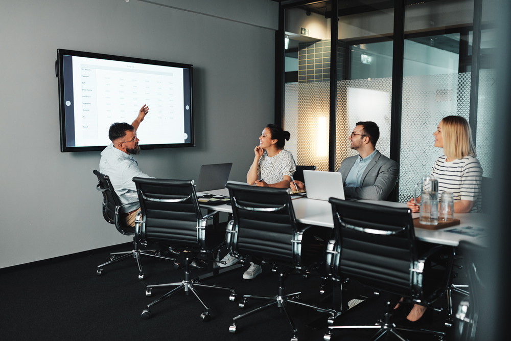 Réunion formelle en salle de concertation entre direction et représentants syndicaux analysant des données projetées à l’écran, illustrant la nécessité d’identifier et traiter un Abus de pouvoir délégué syndical dans un cadre professionnel et juridiquement sécurisé.