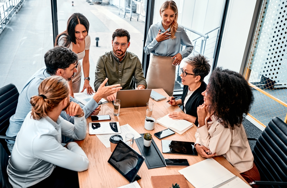 Réunion stratégique en entreprise réunissant direction et représentants autour d’une table avec documents et ordinateur portable, illustrant un dialogue social en restructuration mené sous tension mais dans un cadre structuré de négociation et de concertation.